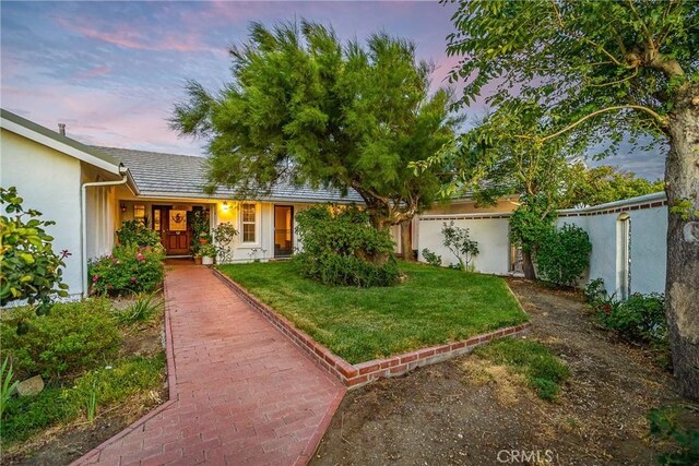 view of front of property featuring stucco siding, a front yard, and fence