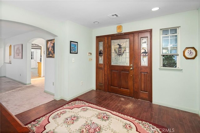 foyer featuring visible vents, arched walkways, baseboards, and wood finished floors