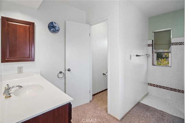 bathroom featuring tiled shower and vanity