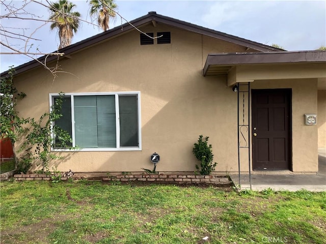 exterior space with stucco siding and a yard