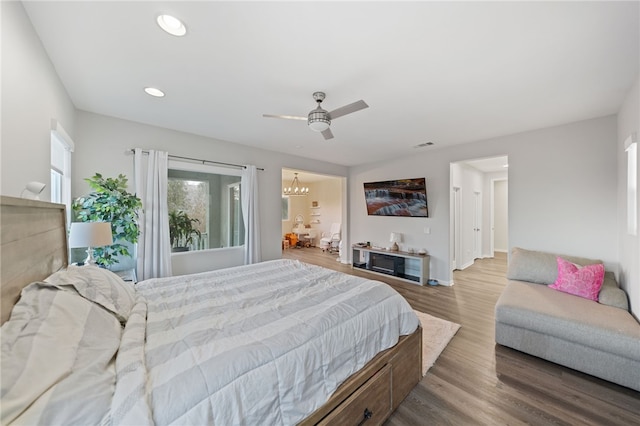 bedroom with wood finished floors, visible vents, baseboards, recessed lighting, and ceiling fan with notable chandelier