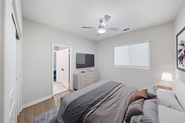 bedroom featuring visible vents, connected bathroom, ceiling fan, baseboards, and wood finished floors