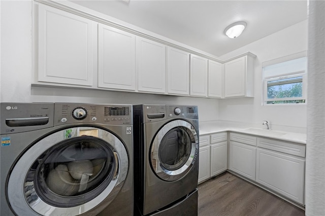 washroom featuring cabinet space, dark wood-style floors, washer and dryer, and a sink