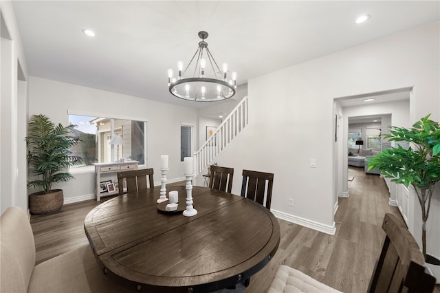 dining room with a chandelier, baseboards, wood finished floors, and stairs