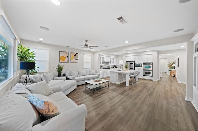 living room featuring baseboards, recessed lighting, visible vents, and light wood-type flooring