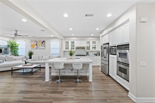 kitchen with visible vents, a breakfast bar, under cabinet range hood, stainless steel appliances, and white cabinets