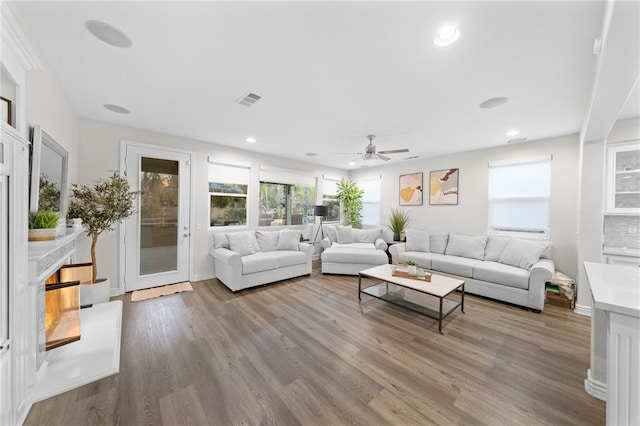 living room with recessed lighting, visible vents, baseboards, and wood finished floors