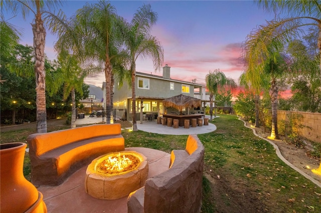 exterior space featuring a patio, a fire pit, fence, and outdoor dry bar