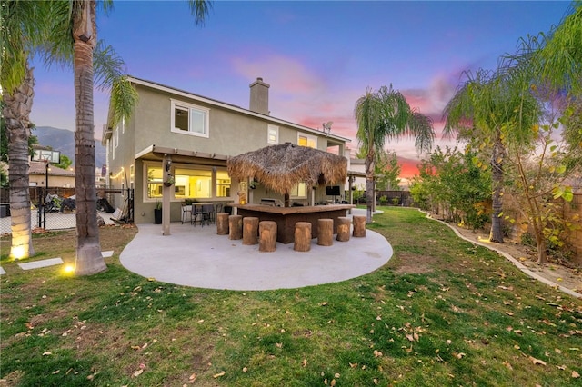 rear view of property with outdoor dry bar, a yard, a patio, and a fenced backyard