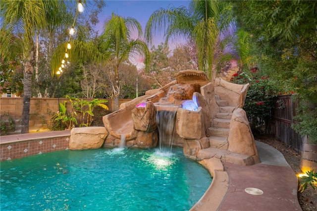 pool at dusk featuring a fenced backyard and a fenced in pool