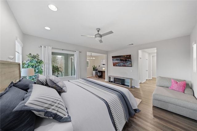 bedroom featuring wood finished floors, visible vents, baseboards, recessed lighting, and ceiling fan with notable chandelier