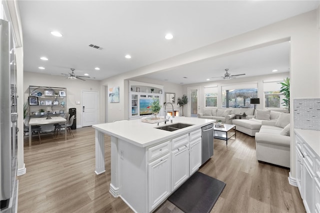 kitchen featuring light wood finished floors, visible vents, open floor plan, appliances with stainless steel finishes, and a sink