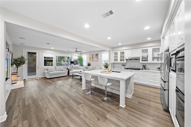 11119 Iris Ct, Corona, CA 92883 - kitchen with stainless steel appliances, under cabinet range hood, recessed lighting, white cabinetry, and light wood finished floors