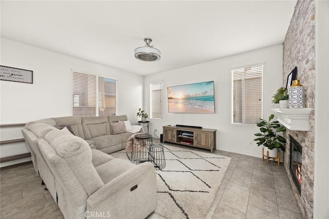 living area featuring light tile patterned floors, a glass covered fireplace, and baseboards