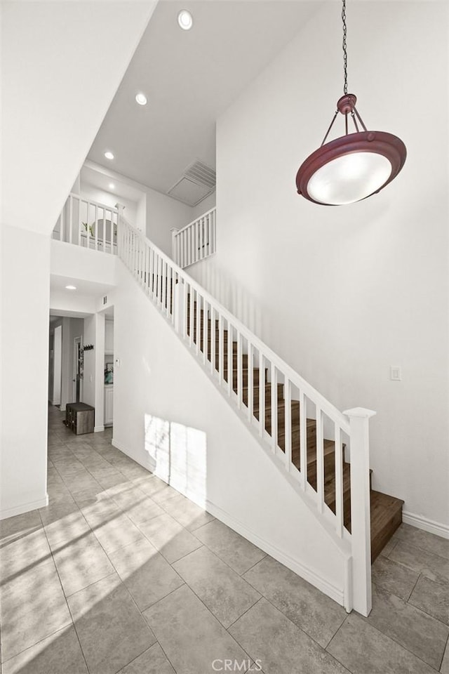 staircase featuring tile patterned flooring, a high ceiling, recessed lighting, and baseboards