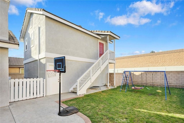 view of side of home featuring a playground, a fenced backyard, and stucco siding