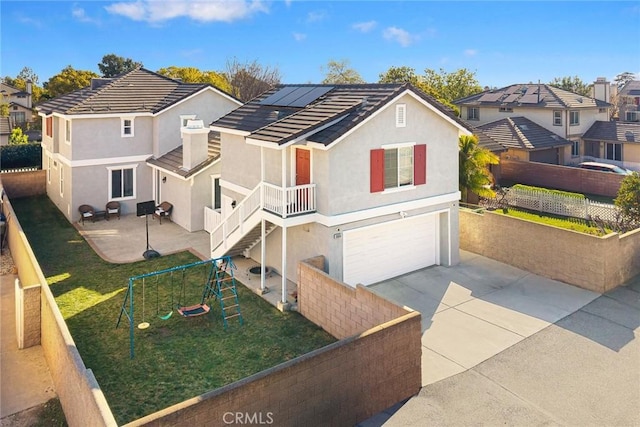 view of front of home with stucco siding, solar panels, a fenced backyard, and driveway