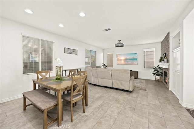 dining area featuring baseboards, visible vents, and a large fireplace