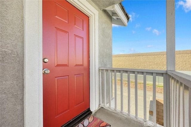 entrance to property with stucco siding and a balcony