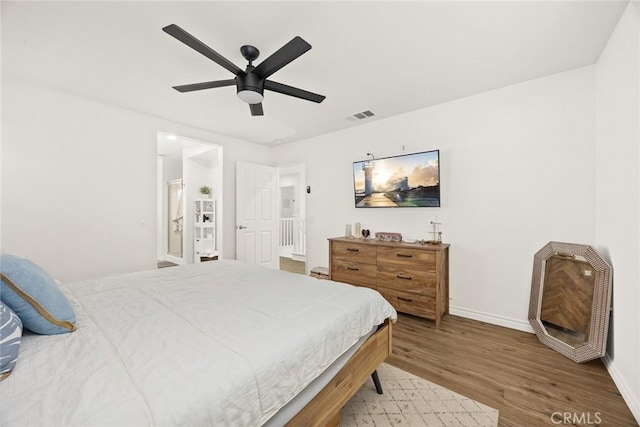 bedroom with ceiling fan, visible vents, baseboards, and wood finished floors