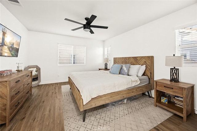 bedroom with visible vents, ceiling fan, baseboards, and wood finished floors