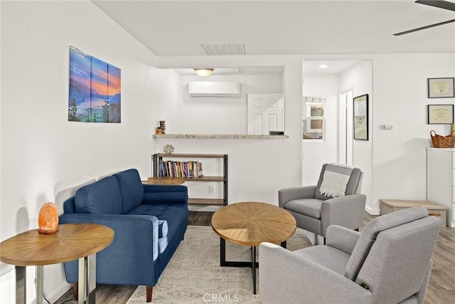 living area with wood finished floors, visible vents, and a wall mounted air conditioner