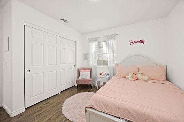 bedroom featuring dark wood finished floors, visible vents, and a closet