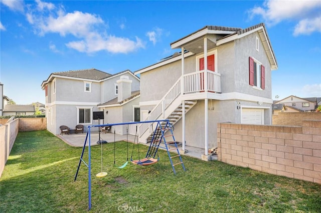 back of property featuring a fenced backyard, stucco siding, a playground, a patio area, and a lawn