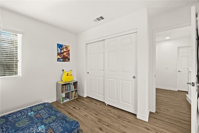 bedroom featuring visible vents, baseboards, a closet, and wood finished floors