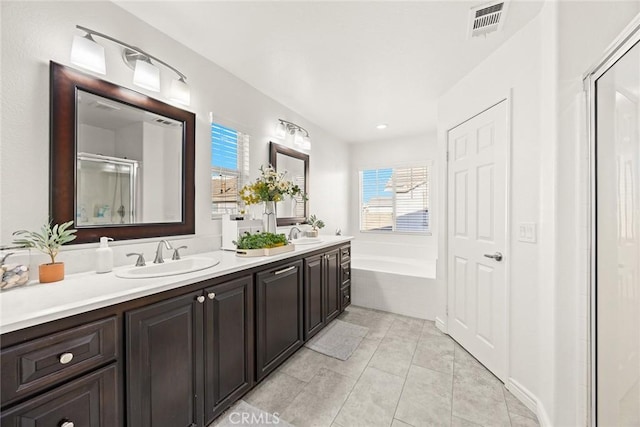 bathroom featuring a garden tub, a sink, a shower stall, tile patterned flooring, and double vanity