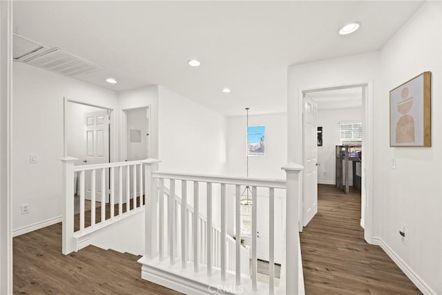 corridor featuring wood finished floors, recessed lighting, an upstairs landing, and baseboards