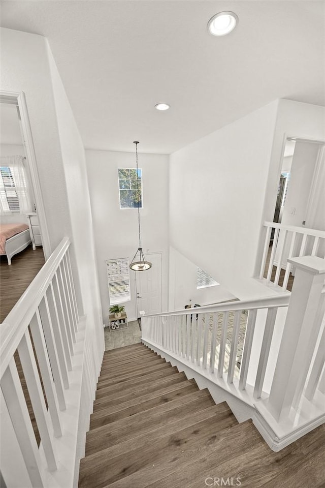 stairway featuring recessed lighting, wood finished floors, and a towering ceiling