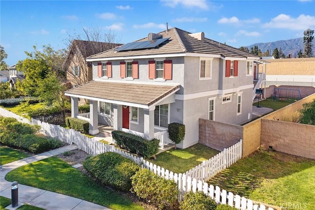 view of front of property with solar panels, a fenced backyard, covered porch, stucco siding, and a tiled roof