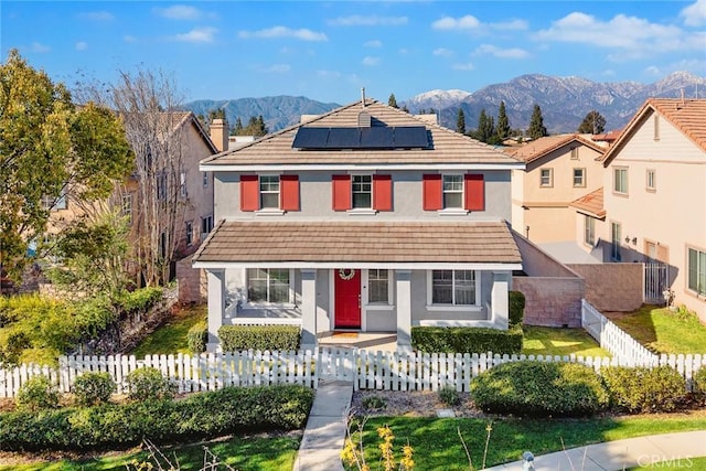 view of front facade featuring a fenced front yard, stucco siding, a mountain view, and a tile roof