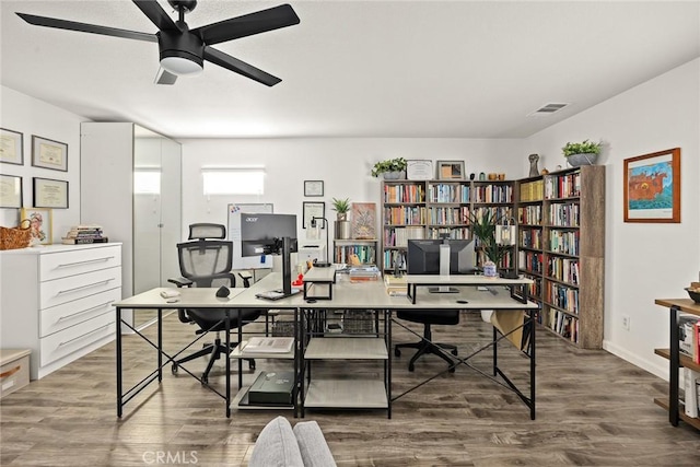 office space featuring wood finished floors, visible vents, and ceiling fan