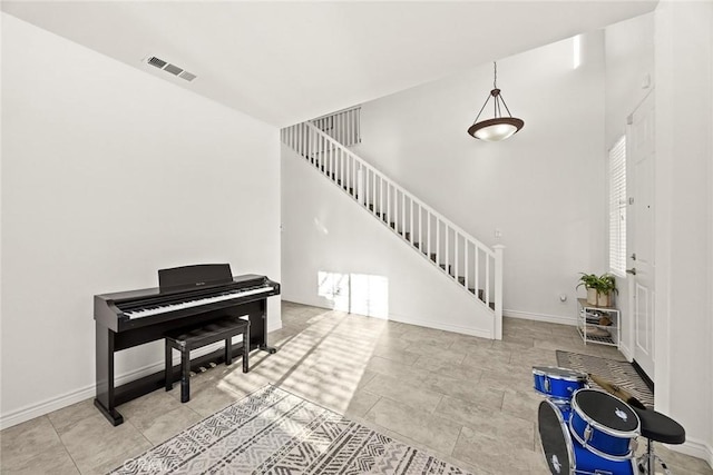 living area featuring visible vents, baseboards, and stairway