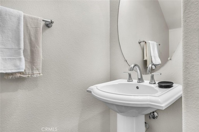 bathroom featuring a sink and a textured wall