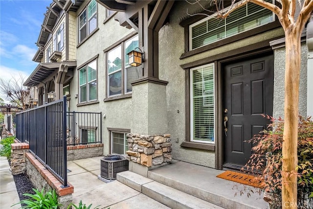 view of exterior entry with cooling unit and stucco siding