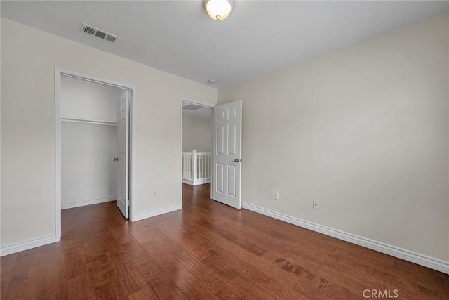 unfurnished bedroom featuring wood finished floors, visible vents, a closet, and baseboards