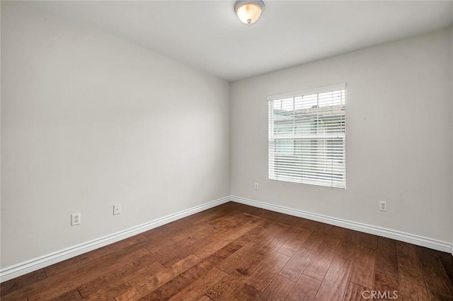 spare room featuring hardwood / wood-style flooring and baseboards