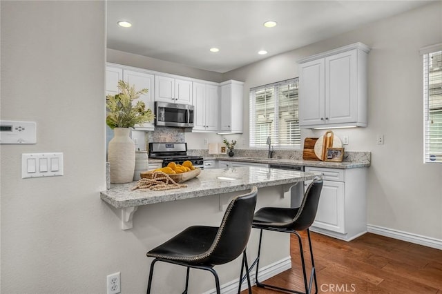 kitchen featuring a kitchen bar, white cabinetry, appliances with stainless steel finishes, and a sink