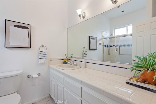 bathroom featuring tile patterned flooring, a shower stall, baseboards, toilet, and vanity