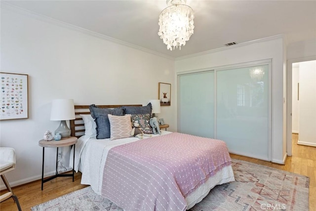 bedroom featuring visible vents, wood finished floors, crown molding, and a chandelier