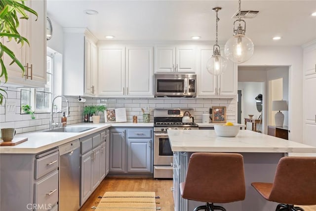 kitchen featuring visible vents, gray cabinets, a sink, stainless steel appliances, and light countertops