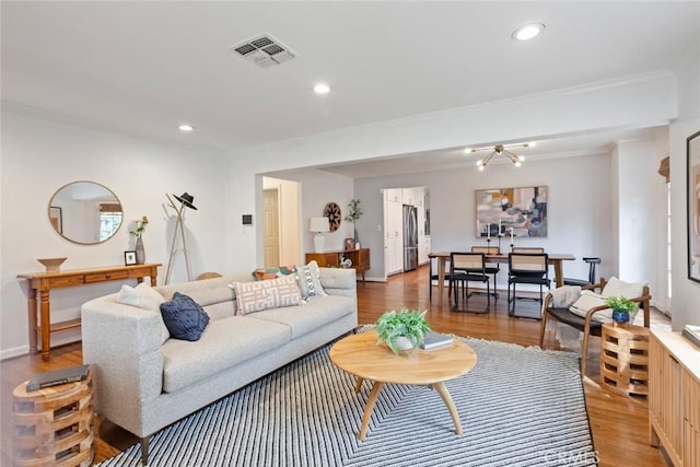 living room with visible vents, recessed lighting, light wood-type flooring, and ornamental molding