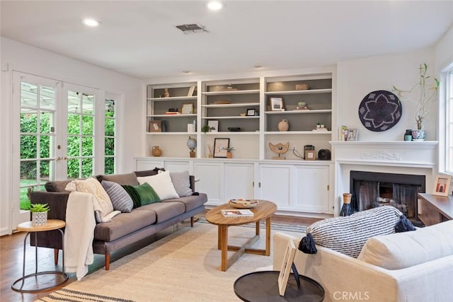 living area featuring wood finished floors, visible vents, a fireplace, recessed lighting, and french doors