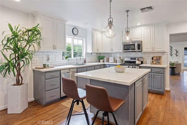 kitchen with a sink, stainless steel appliances, gray cabinetry, and visible vents