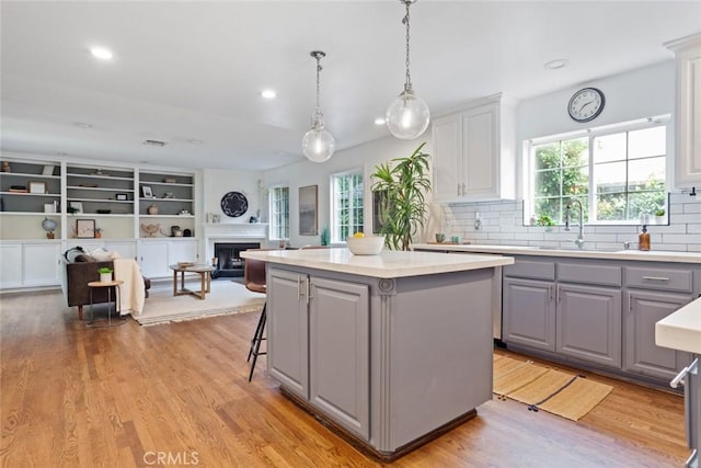 kitchen featuring gray cabinets, a sink, open floor plan, light wood-type flooring, and a center island