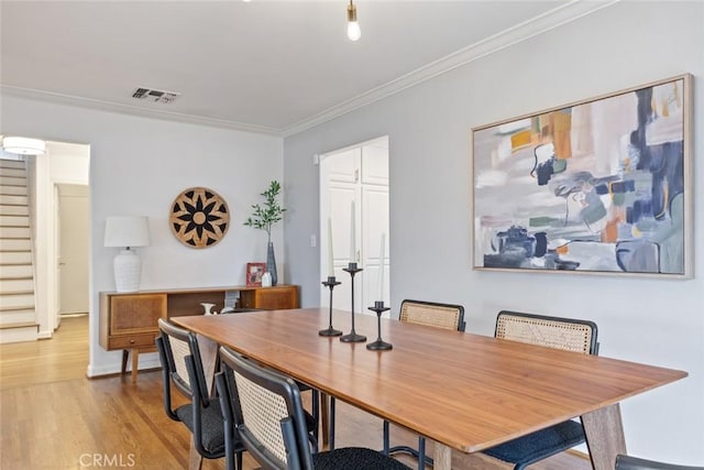 dining room with visible vents, light wood-style flooring, crown molding, and stairway