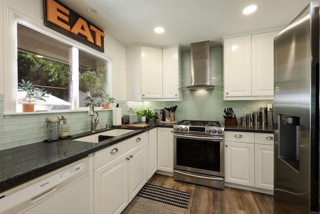 kitchen with a sink, wall chimney range hood, white cabinetry, and stainless steel appliances